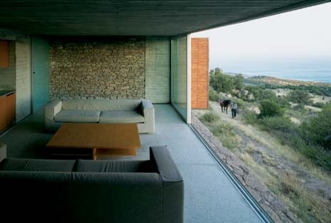 The straw-mat shutters and glass panels can be drawn apart, opening up the facade to sweeping views of the sea