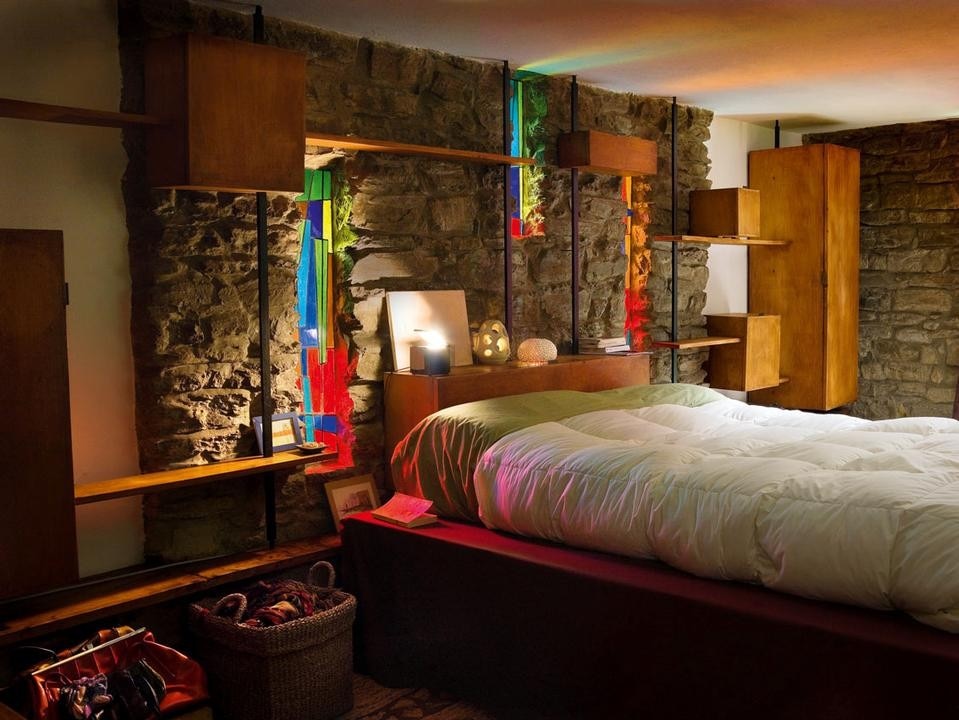 The bedroom occupy the upper and
lower levels, respectively, of the southwest
zone, behind the bare stone wall with Ricci’s
original stained glass and furniture