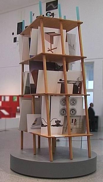 Lo scaffale di Grcic è superdimensionato e contiene cartellone di presentazione dei suoi lavori